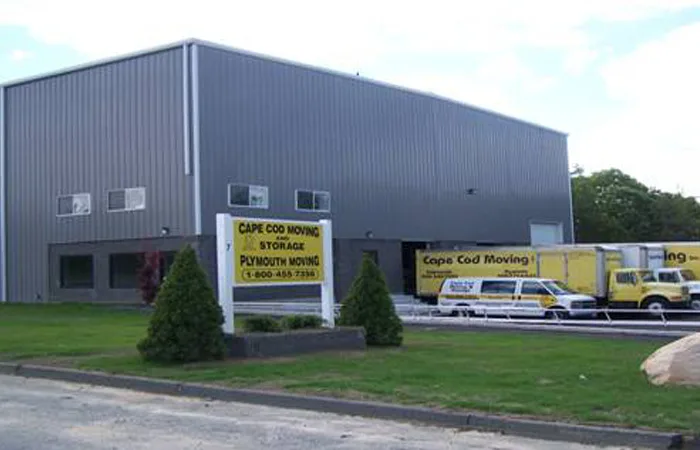 Gray warehouse building with yellow moving trucks parked at the loading docks
